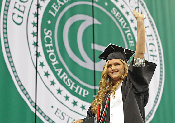 Picture of Graduating student with a Graduation Ceremony Banner